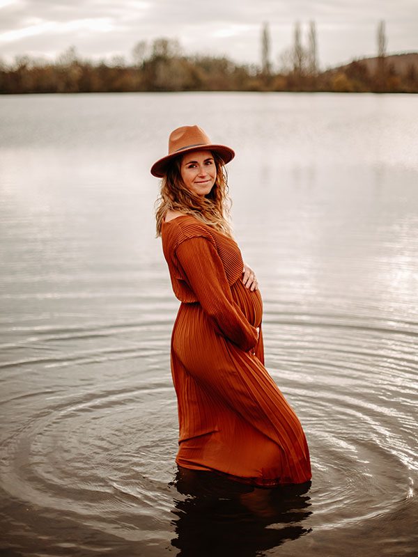 jeune femme enceinte avec une longue robe les pieds dans l'eau dans un étang en à Cond-sur-Risle en Normandie