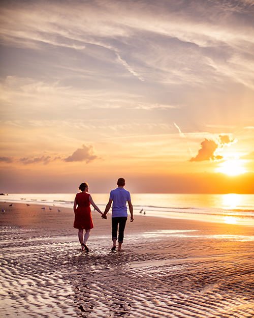 photo d'un couple marchant main dans la main sur le sable en Normandie